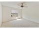 A bright bedroom with white walls, light carpet and a ceiling fan has a window looking out to the street at 26622 S Beech Creek Dr, Sun Lakes, AZ 85248
