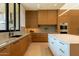 Modern kitchen featuring sleek wood cabinets, a white island, and stainless steel appliances at 3643 E Coolidge St, Phoenix, AZ 85018