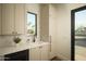 Modern laundry room with shaker cabinets, stainless steel appliances and a window overlooking the backyard at 5327 N Invergordon Rd, Paradise Valley, AZ 85253