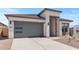 Modern single-story home featuring a gray garage door with windows, stone accents and desert landscaping at 564 E Aurora Dr, San Tan Valley, AZ 85140