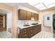 A well-lit kitchen featuring wood cabinets and a double basin sink underneath a skylight at 10329 W Manzanita Dr, Sun City, AZ 85373