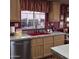 Bright kitchen showcases a red sink under a window with wooden cabinets and stainless steel appliances, plus decorative wall art at 11411 N 91St Ave # 225, Peoria, AZ 85345