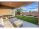 Covered patio with seating area and built-in grill overlooks grassy backyard at 12133 W Desert Moon Way, Peoria, AZ 85383