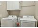 Functional laundry room featuring side-by-side washer and dryer, overhead cabinets, and ample space at 16954 W Palm Ln, Goodyear, AZ 85395