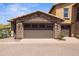 A large two car garage featuring a stone facade and a neutral brown door at 17763 N 93Rd Way, Scottsdale, AZ 85255