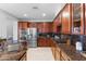 Kitchen featuring stainless appliances, dark wood cabinets, granite countertops, and breakfast bar at 17763 N 93Rd Way, Scottsdale, AZ 85255