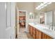 Bathroom with double sink vanity, wood cabinets, and doorway to an office space at 41515 N Laurel Valley Way, Anthem, AZ 85086