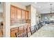A well-appointed kitchen with wooden cabinets, granite countertops, and a view into the living area at 41515 N Laurel Valley Way, Anthem, AZ 85086
