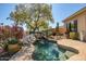 Freeform pool with rock waterfall feature, lush desert plants, and a sculpture make this backyard a true oasis at 41515 N Laurel Valley Way, Anthem, AZ 85086