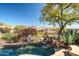 Desert landscaping surrounds a pool with rocks, a small waterfall, and views of mountains in the distance at 41515 N Laurel Valley Way, Anthem, AZ 85086
