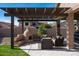 Cozy outdoor patio with a pergola, custom fireplace, comfortable seating, and green lawn at 4415 E Weaver Rd, Phoenix, AZ 85050