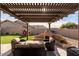 Inviting backyard patio under a pergola with a built-in fireplace, seating and landscaped yard at 4415 E Weaver Rd, Phoenix, AZ 85050