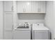 Well-organized laundry room with side-by-side washer and dryer and storage cabinets above at 5112 E Voltaire Ave, Scottsdale, AZ 85254