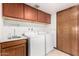 Functional laundry room equipped with a sink, washer, dryer, and storage cabinets at 6604 W Evans Dr, Glendale, AZ 85306