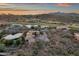 Aerial view of desert homes near a golf course with mountains, lit by a colorful sky at sunset at 9815 N Copper Ridge Trl, Fountain Hills, AZ 85268