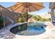 A backyard pool features a rock waterfall, an umbrella, and decorative metal turtles on the block wall at 15804 N 109Th Dr, Sun City, AZ 85351