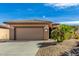 Tan house with a two-car garage and desert landscaping at 18727 N Desert Light Dr, Surprise, AZ 85387