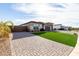 Long brick driveway leading to a three-car garage, complemented by lush, artificial turf landscaping at 1983 E Sarona Ct, San Tan Valley, AZ 85143