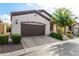 Tan stucco home with brown garage door, landscaping, and paved driveway at 2049 N 88Th St, Mesa, AZ 85207