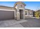 Home exterior featuring gray colors, a large driveway, and stone pillar accents at 24134 N Cotton Cir, Florence, AZ 85132