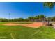 View of the community baseball field with manicured grass and protective fencing, ideal for games and practice at 25948 W Sands Dr, Buckeye, AZ 85396