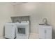 Well-equipped laundry room with washer, dryer, sink, and storage shelf at 25948 W Sands Dr, Buckeye, AZ 85396