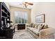 Bright home office features built-in shelving, a comfortable sofa, and large window with plantation shutters at 27379 N Makena Pl, Peoria, AZ 85383