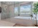 Close up of the glass enclosed shower and soaking tub with view outside at 2967 E Boot Track Trl, Gilbert, AZ 85296