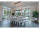 Bright dining area featuring a large table, modern chandelier, and sliding glass doors to the backyard and patio at 2967 E Boot Track Trl, Gilbert, AZ 85296