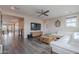 Bright living room with a modern ceiling fan, hardwood floors, a large TV, and comfortable seating at 2967 E Boot Track Trl, Gilbert, AZ 85296