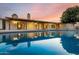 Backyard pool reflecting the house at dusk with a covered patio and lush foliage at 302 E Coral Gables Dr, Phoenix, AZ 85022