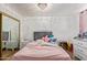 Bedroom with a pink comforter, white dresser and nightstand, and mirrored closet doors at 8501 W Glenrosa Ave, Phoenix, AZ 85037