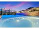 A stunning pool with a modern waterfall feature and ambient lighting creates a relaxing backyard oasis at 11517 E Unity Ave, Mesa, AZ 85212