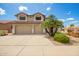 Two-story tan home featuring a three-car garage, desert landscaping, and a red tile roof at 19520 N 65Th Ave, Glendale, AZ 85308