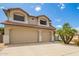 Two-story tan home featuring a three-car garage, desert landscaping, and a red tile roof at 19520 N 65Th Ave, Glendale, AZ 85308