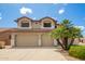 Two-story tan home featuring a three-car garage, desert landscaping, and a red tile roof at 19520 N 65Th Ave, Glendale, AZ 85308