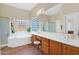 Well-lit bathroom featuring dual sinks, ample counter space, soaking tub, and glass block window at 11222 E Oberlin Way, Scottsdale, AZ 85262