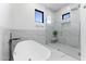 Modern bathroom features white marble walls and floor, free standing tub, and glass shower at 12560 E Cochise Dr, Scottsdale, AZ 85259