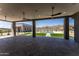 Covered patio with ceiling fans, looking out on backyard with pool, turf, pavers and desert mountain views at 12560 E Cochise Dr, Scottsdale, AZ 85259