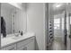 This bathroom features white cabinets, a sleek mirror, and a shower with a stylish striped curtain at 14369 W Wethersfield Rd, Surprise, AZ 85379