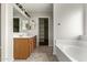 Bright bathroom features double sinks, wood cabinets, tiled floors, and a separate soaking tub and closet at 15118 W Lincoln St St, Goodyear, AZ 85338