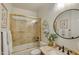 Bathroom featuring a tub/shower combo with glass doors, a round mirror, and decorative accents at 1560 W Augusta Ave, Phoenix, AZ 85021