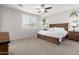 Main bedroom with wooden bed frame and ceiling fan, carpeted floors at 19042 W Clinton St, Surprise, AZ 85388