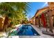 Serene backyard with a sparkling pool, stone accents, lush palm trees, and covered patio at 20620 W Walton Dr, Buckeye, AZ 85396