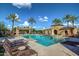 Resort-style community pool featuring palm trees, lounge seating, and a building with archway entrance at 20620 W Walton Dr, Buckeye, AZ 85396