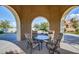 Cozy covered seating area with neutral upholstered chairs, glass table and desert landscaping at 20620 W Walton Dr, Buckeye, AZ 85396