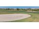 A golf course sand bunker on a sunny day, surrounded by green grass and homes in the background at 20620 W Walton Dr, Buckeye, AZ 85396