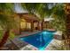 A serene pool is surrounded by stonework and palm trees with an outdoor living space under a covered patio at 20620 W Walton Dr, Buckeye, AZ 85396