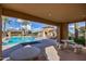 View of the pool from the covered poolside patio with tables, chairs, and lounging space at 20620 W Walton Dr, Buckeye, AZ 85396