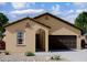 Tan house with brown garage door, arched entryway, and desert landscaping at 38123 N Stallion St, San Tan Valley, AZ 85140